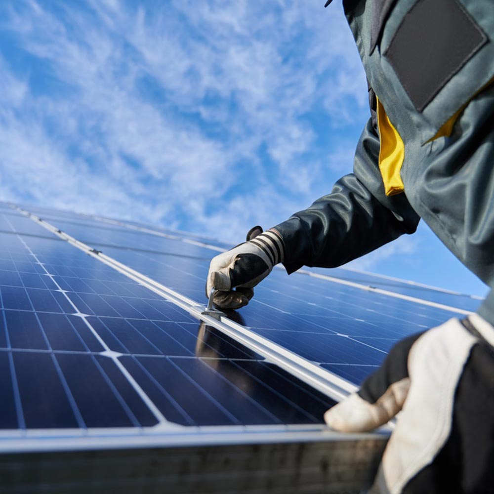 Electrician installing new solar panels on a roof top.